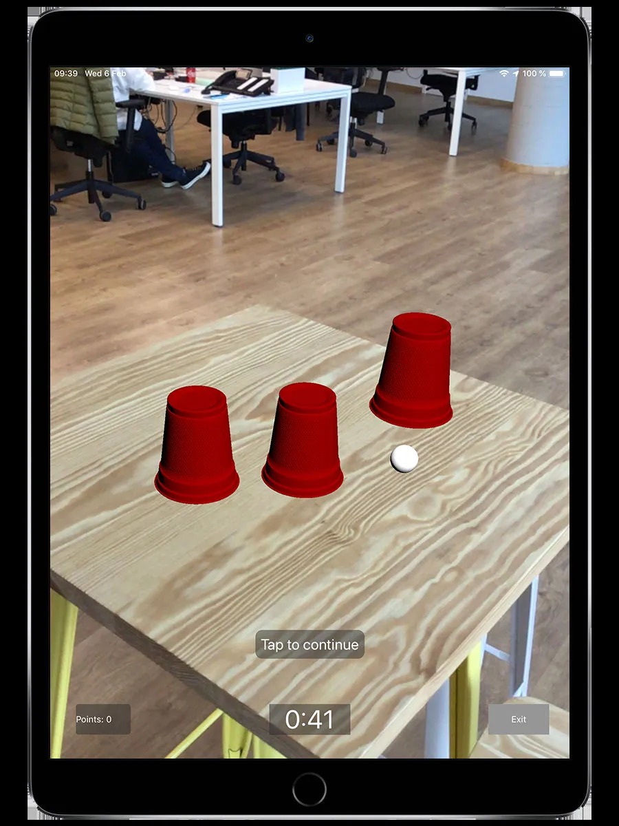 Shell Game challenge screen showing three red cups on a table in augmented reality